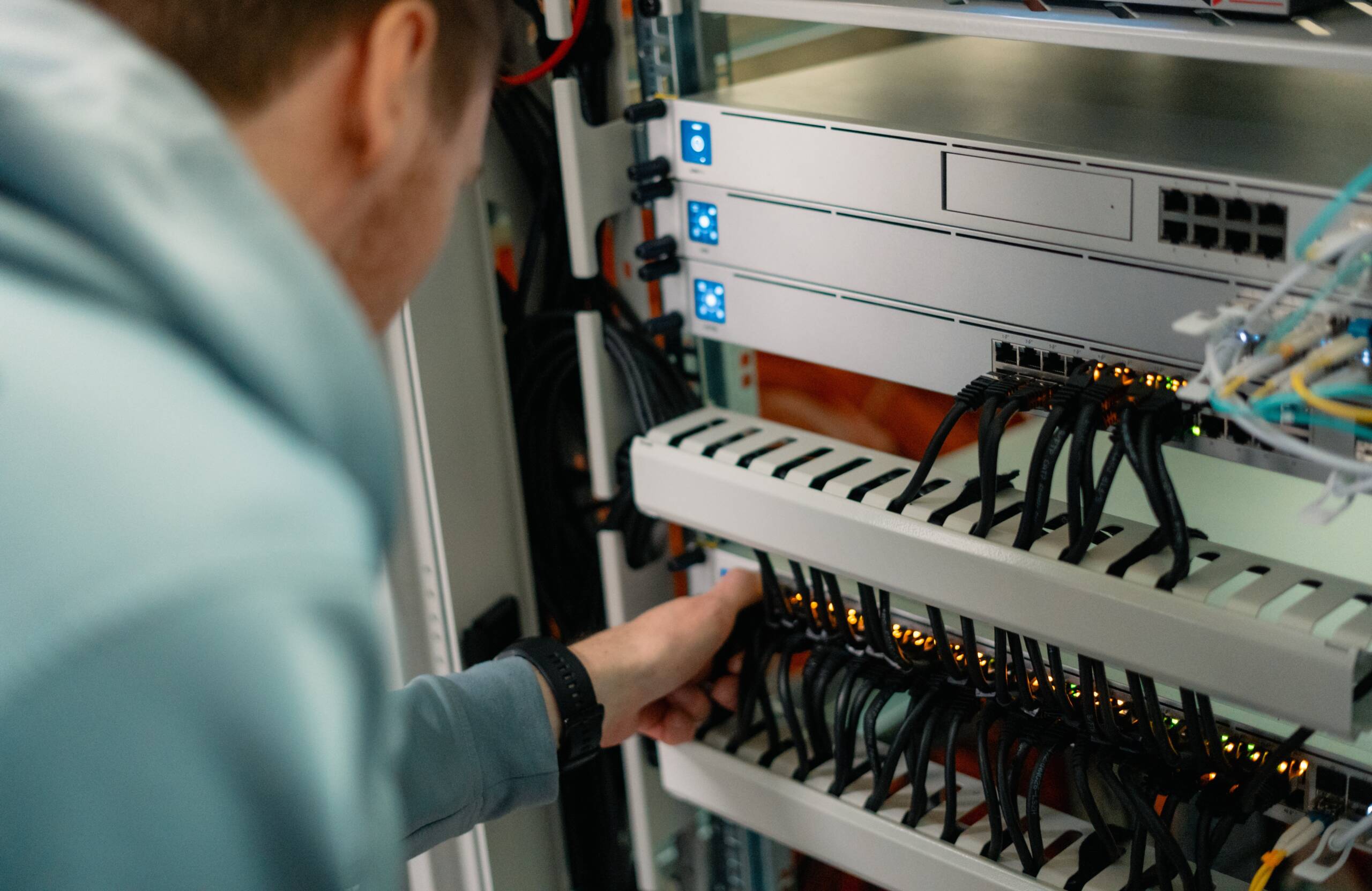 IT-Techniker verkabelt Switches in einem Netzwerkschrank mit strukturierter Kabelführung